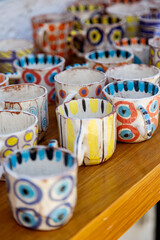 colorful ceramic cups on wooden table retale outdoors