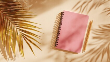 Pink notebook, pencils, and palm fronds on beige background, sunlit shadows