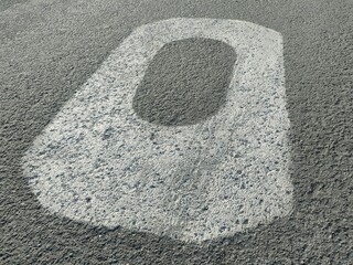 Close-up of a white painted number “0” on textured asphalt. Worn surface and bold contrast ideal for urban design, signage, or transportation themes