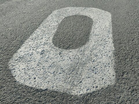 Close-up of a white painted number “0” on textured asphalt. Worn surface and bold contrast ideal for urban design, signage, or transportation themes