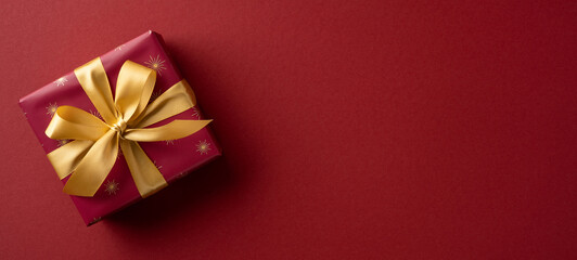 A festive red gift box tied with a gold ribbon sits on a rich red backdrop, capturing holiday warmth, celebration, and the spirit of Christmas and New Year