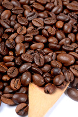 A close-up shot of roasted coffee beans with a wooden scoop partially visible.