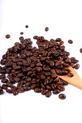 Close-up shot of roasted coffee beans scattered on a white surface with a wooden spoon.