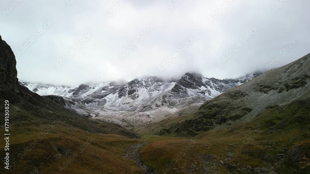 Poster pullback aerial view of a snowy mountain nestled within a valley.