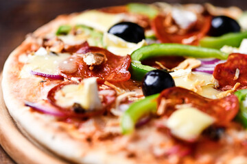 Pizza with chorizo ​​sausage, mozzarella cheese, green pepper and black olives. Rustic wooden background. Soft focus.	