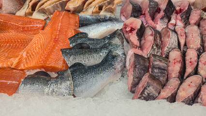 Frozen sea and freshwater fish on a supermarket shelf Sliced and whole Seafood