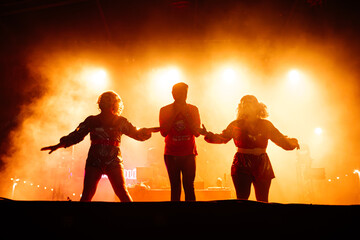 Fototapeta premium Silhouetted Drag Queens Commanding the Stage at a Vibrant Evening Performance