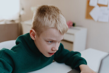 A boy with hearing aids focuses intently while playing a game on his laptop, showcasing modern adaptive technology and inclusive digital entertainment for children with hearing disabilities