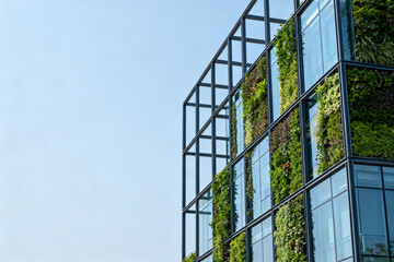 Modern building with vertical green wall and glass facade against clear blue sky