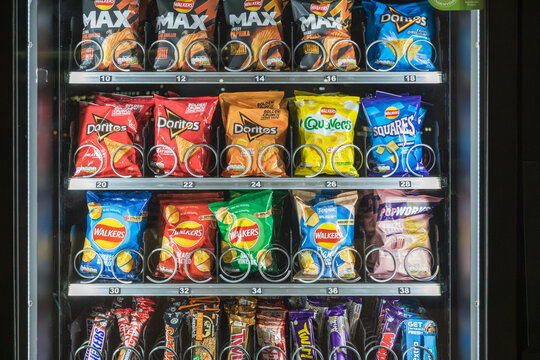 A vending machine filled with a variety of crisps and snacks, including Walkers, Doritos, Quavers, and Squares