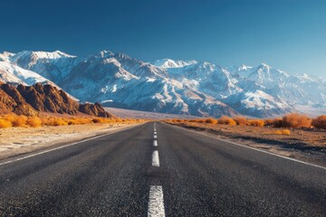 Naklejka premium Serene Desert Road with Majestic Snow-Capped Mountains in Background
