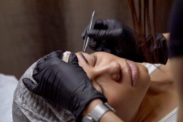 Woman receiving eyebrow grooming service in a beauty salon during a relaxing afternoon appointment...