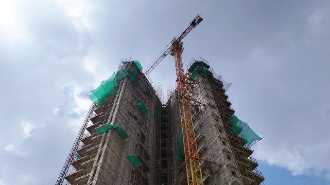 Drone aerial shot of crane at construction site with building in background