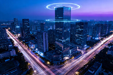 Fototapeta premium Nighttime cityscape with illuminated skyscrapers and light trails from traffic, featuring a futuristic glowing ring above a central building