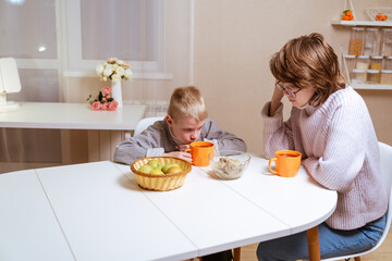 A boy with hearing aids and his mother share a warm conversation over tea in their cozy kitchen. A tender moment of family bonding, communication, and inclusive love