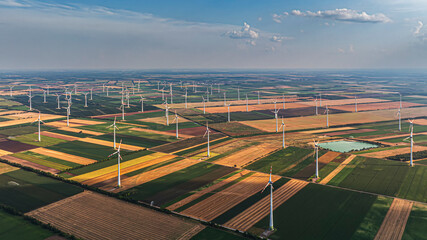 Modern wind turbines rise above farmland, generating clean energy for a sustainable future. Wind...