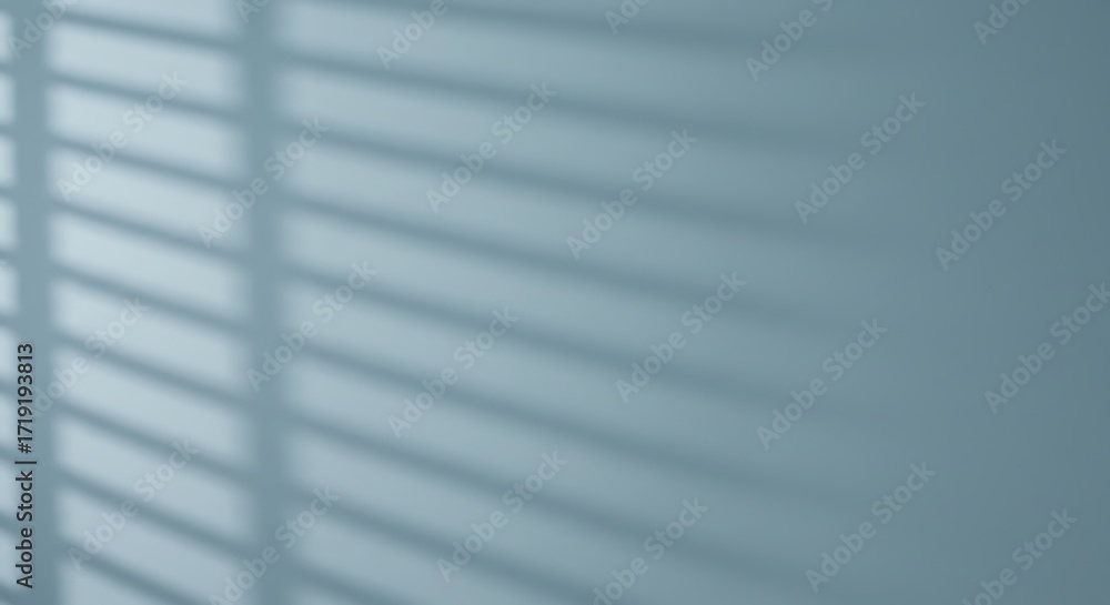 Poster shadows of blinds on a blue wall create an abstract pattern.