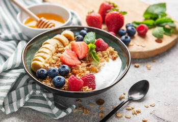 Delicious granola with yogurt, fresh berries and banana slices enjoying healthy breakfast