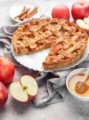 Apple pie with slice removed surrounded by fresh apples