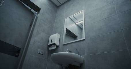 Male Office Worker Looking in the Mirror, Washing His Hands with Soap in the Sink. Hand Hygiene after Using the Toilet. Businessman Doing Daily Routine in Office Restroom During Work. Lifestyle.