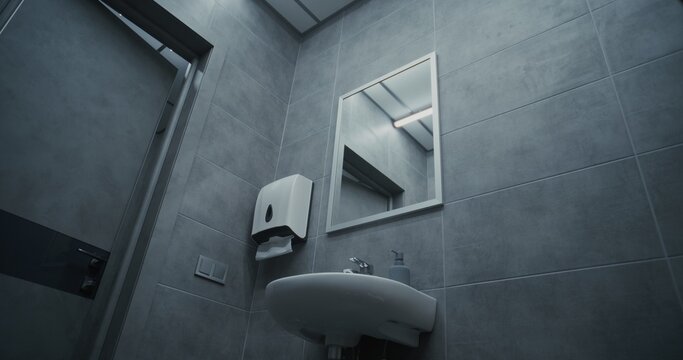 Male Office Worker Looking in the Mirror, Washing His Hands with Soap in the Sink. Hand Hygiene after Using the Toilet. Businessman Doing Daily Routine in Office Restroom During Work. Lifestyle.