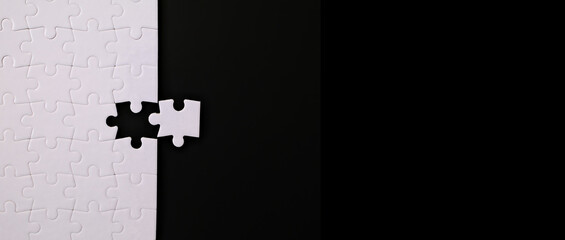 jigsaw puzzle with one piece left on black background with empty space, completing a task or solving a problem