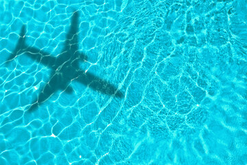 Naklejka premium Flying airplane casting shadow on water, top view