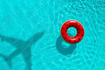 Inflatable ring floating in swimming pool, top view. Flying airplane casting shadow on water