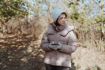 Fototapeta premium A young woman in a park uses her phone to navigate, enjoying nature while finding her way. Captures modern exploration, relaxation, and technology in daily life