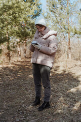 A young woman in a park uses her phone to navigate, enjoying nature while finding her way. Captures modern exploration, relaxation, and technology in daily life