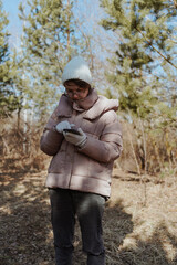 A young woman in a park uses her phone to navigate, enjoying nature while finding her way. Captures modern exploration, relaxation, and technology in daily life