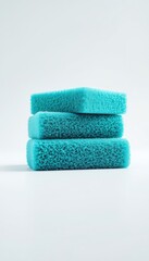 Stack of three rectangular teal sponges used for household chores on a plain white background