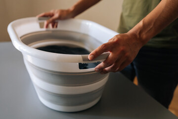 Close-up cropped shot of unrecognizable man preparing to housework, washing clothes by hand or other cleaning tasks standing by table. Concept of domestic work, housekeeping and household.