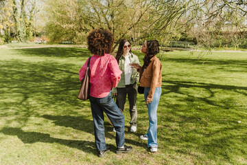 Fototapeta premium A woman is talking to two female friends standing next to her while one of them is smiling
