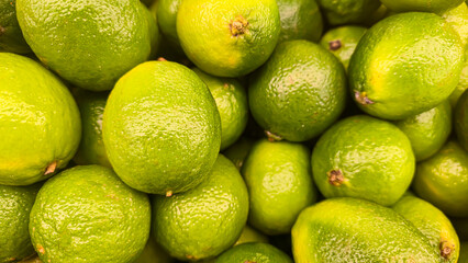 Green limes in large crates on store shelves. Display and sale of citrus fruits.