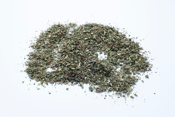 pile of dried and chopped basil spice on white background