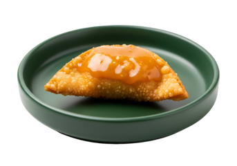 Golden-brown pastry filled with a savory sauce sits on a dark-green plate against a black backdrop.