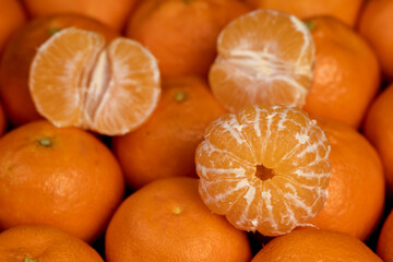 peeled orange tangerines are stacked together, a large number of ripe orange tangerines are on the table and peeled tangerines