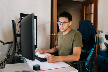 Focused programmer male typing on mechanical keyboard, working remotely from home workspace with professional concentration. Programming language development technology, freelance job concept.