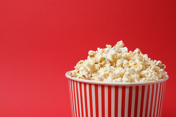 Classic red and white striped box filled with delicious, fluffy popcorn, 3D glasses on a red background.
