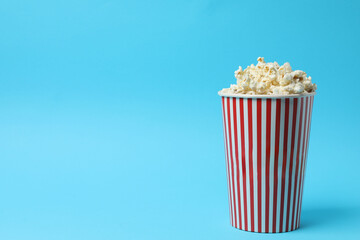 Classic red and white striped box filled with delicious, fluffy popcorn, 3D glasses on a blue background.
