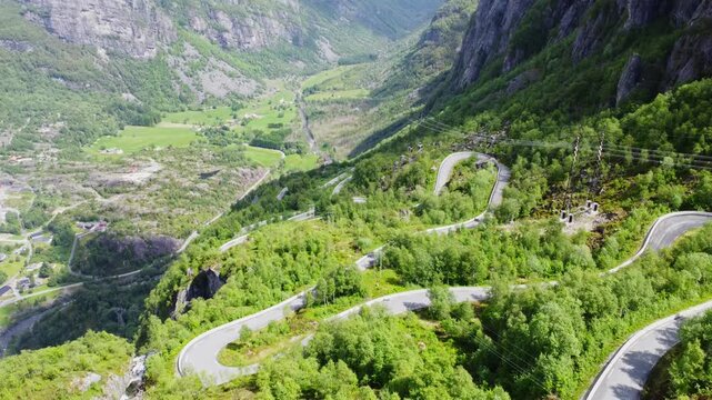 Aerial view of the serpentine Lysevegen road snaking through vibrant green forests and rugged terrain, a scenic route, Lysebotn, Rogaland, Norway.
