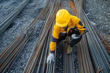 Steel Reinforcement Inspection: A construction worker, donned in protective gear, meticulously inspects a network of steel reinforcement bars at a construction site. Focused and dedicated.