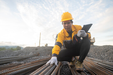  An attentive construction worker, dressed in protective attire, meticulously inspects a bundle of rebar on a construction site.