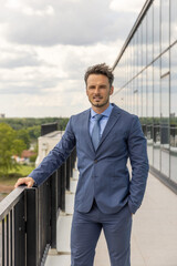 Businessman in a suit standing on the terrace of an office building