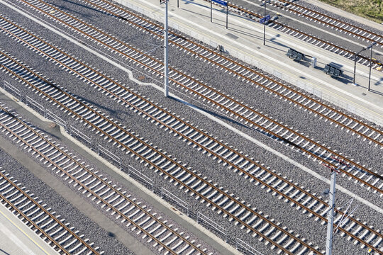 Aerial view of parallel train tracks glinting under the sun, a stark contrast against the dark ballast stones, Deutschlandsberg, Styria, Austria.