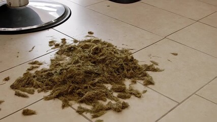 Hair clippings on light beige tile floor near a barber chair