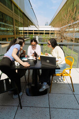 A group of four female students at a table looking at a phone held by one of them