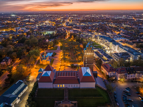 Fototapeta Aerial view of the illuminated Hochzeitsturm and MathildenhÃ¶he in the evening glow, with city lights twinkling below, Darmstadt, Hessen, Germany.