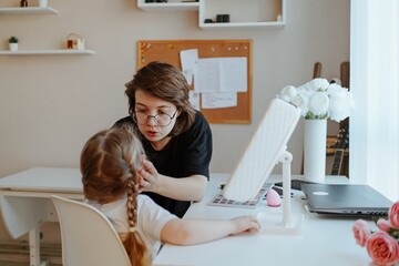 A young mother and her 3-year-old daughter play dress-up as makeup artists, sharing laughter and...
